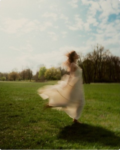 A figure turning in a bright open field, dress caught in motion