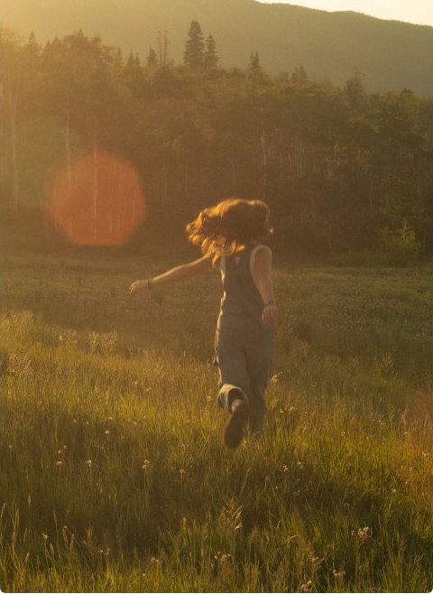 A figure running through a sunlit meadow at golden hour