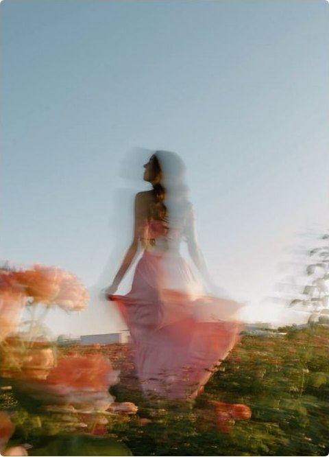 A figure turning among blossoms in soft motion blur under open sky